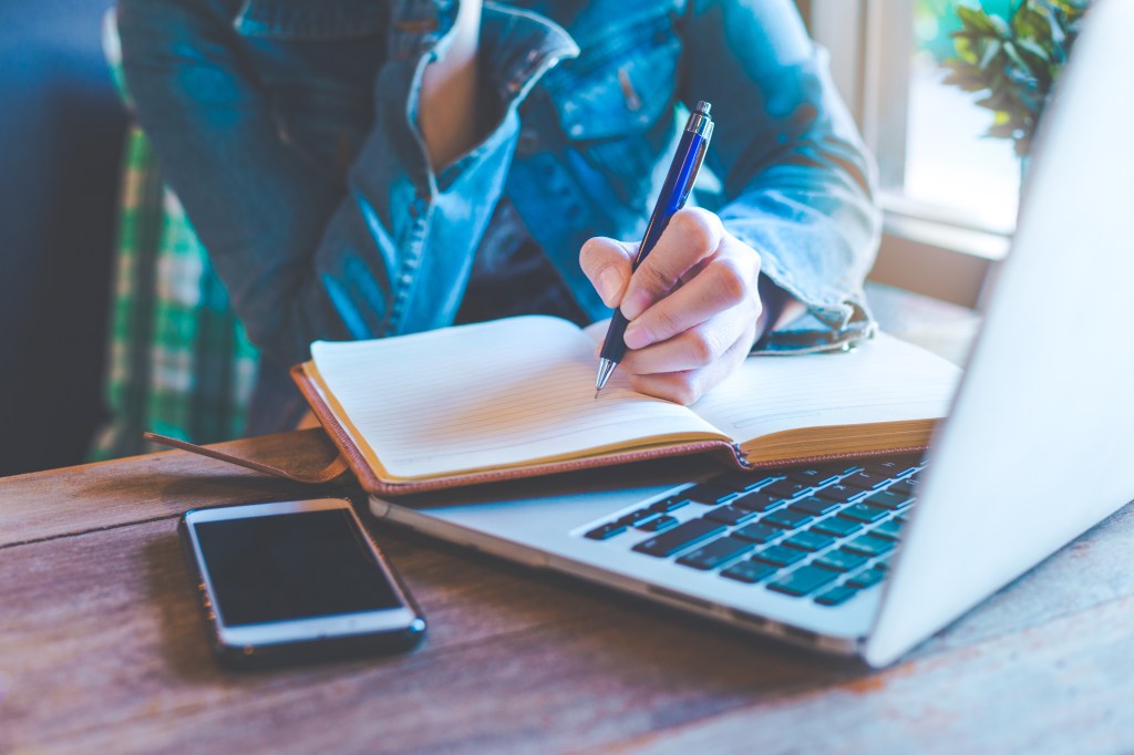 Woman hands with pen writing on notebook.